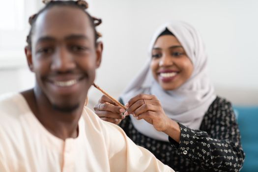 young afro muslim couple have romantic time at home while woman making hairstyle to husband female wearing  traditional sudan islamic hijab clothes