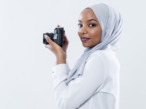 young  african modern muslim woman using retro camera wearing hijab clothes isolated on white background