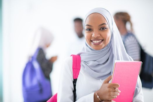 african female student with group of friends in background  wearing traditional Islamic hijab clothes