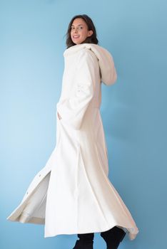 portrait of Beautiful young woman wearing a white coat with hood isolated on blue background