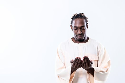 Handsome Young  African Muslim Man Making Traditional Fatiha Prayer To Allah God While Wearing A Traditional Sudan fashion clothes in studio
