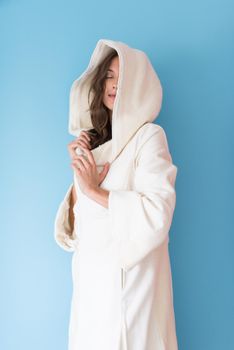 portrait of Beautiful young woman wearing a white coat with hood isolated on blue background