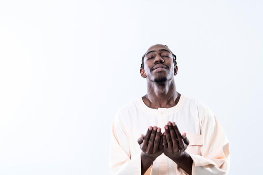 Handsome Young  African Muslim Man Making Traditional Fatiha Prayer To Allah God While Wearing A Traditional Sudan fashion clothes in studio