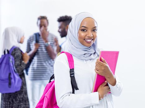 portrait of young african modern muslim female student with group of friends in background  wearing traditional Islamic hijab clothes