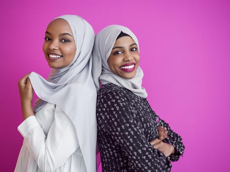 portrait of two young modern muslim afro beauty wearing traditional islamic clothes on plastic pink background