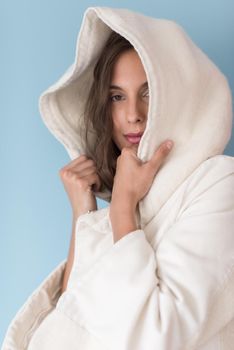 portrait of Beautiful young woman wearing a white coat with hood isolated on blue background