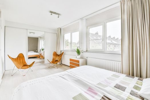 Double bed with soft mattress in a luxurious bedroom with unusual brown chairs