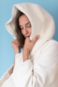 portrait of Beautiful young woman wearing a white coat with hood isolated on blue background