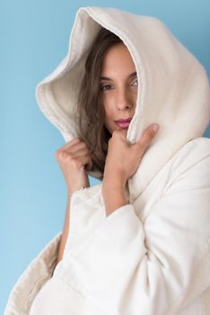 portrait of Beautiful young woman wearing a white coat with hood isolated on blue background