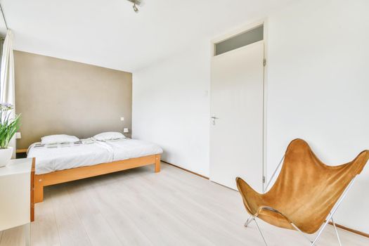 Double bed with soft mattress in a luxurious bedroom with unusual brown chairs