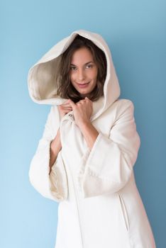 portrait of Beautiful young woman wearing a white coat with hood isolated on blue background