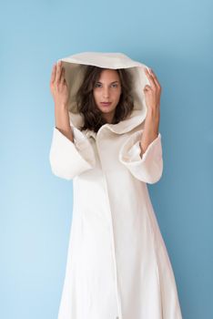 portrait of Beautiful young woman wearing a white coat with hood isolated on blue background