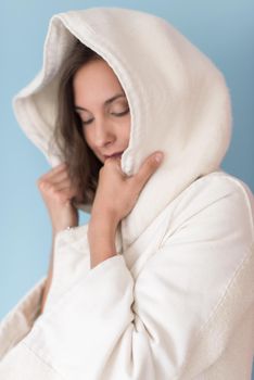 portrait of Beautiful young woman wearing a white coat with hood isolated on blue background