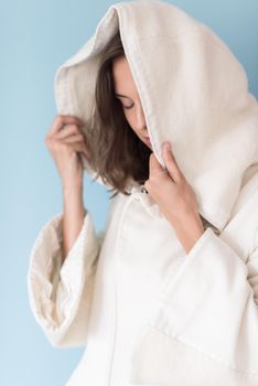 portrait of Beautiful young woman wearing a white coat with hood isolated on blue background