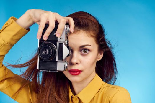 pretty woman photographer with camera in yellow shirt on blue background. High quality photo