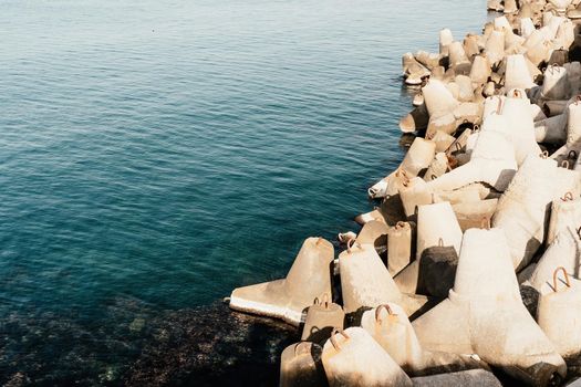 The seashore is reinforced with concrete tetrapods. Protection of the shore from blurring. Sea waves. Concrete tetrapod breakwaters lie all along the coast.