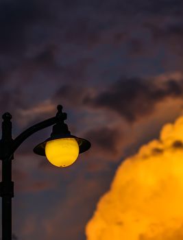 Background of a bright colorful sunset with orange clouds and a yellow street lamp. High quality photo