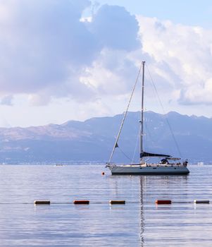 Blue sea, a boat and mountains in sunrise. Tranquil seascape and coastal nature concept