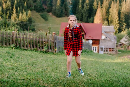 Little girl look into the distance on a grassy hill. portrait of a girl against the panorama of the Alps. happy children girl on spring flowers meadow