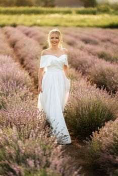 the bride in a white dress walks on the lavender field