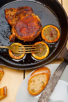 pork chop seared on iron skillet with lemon and spices seasoning