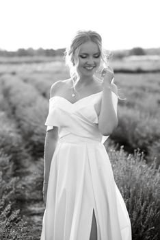 the bride in a white dress walks on the lavender field