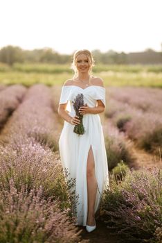 the bride in a white dress walks on the lavender field