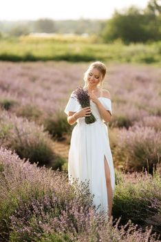 the bride in a white dress walks on the lavender field