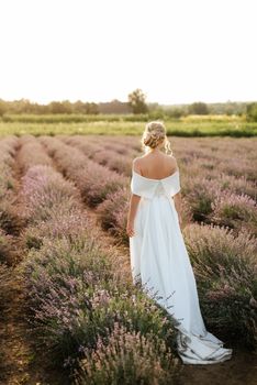 the bride in a white dress walks on the lavender field