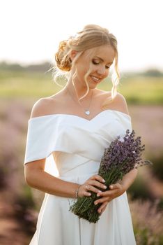 the bride in a white dress walks on the lavender field