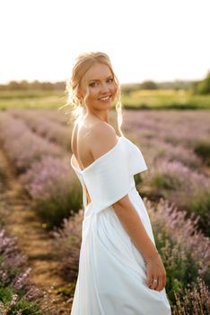 the bride in a white dress walks on the lavender field