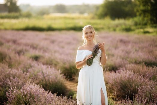 the bride in a white dress walks on the lavender field