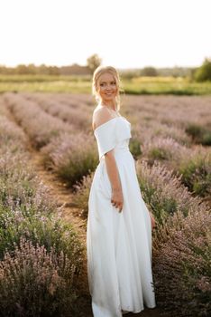 the bride in a white dress walks on the lavender field