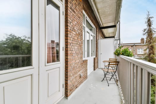 Elegant narrow and long balcony with wooden table and chairs