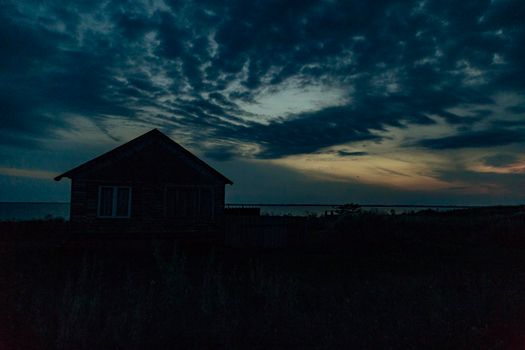 Old Wooden House by the Sea. Wonderful Sunset Landscape with a Dark Blue Sky.