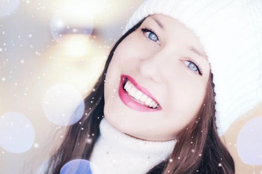 Christmas, people and winter holiday concept. Happy smiling woman wearing white knitted hat as closeup face xmas portrait, snow glitter and bokeh effect.