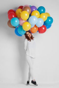 Full length of a happy woman holding balloons against white background