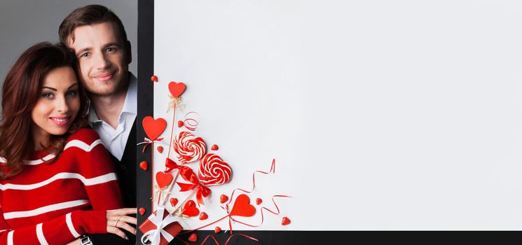 Happy young couple with heart shaped red decoration on white banner background with copy space for text, Valentine's day celebration