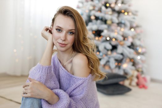 Portrait of a young woman at home near christmas tree. High quality photo