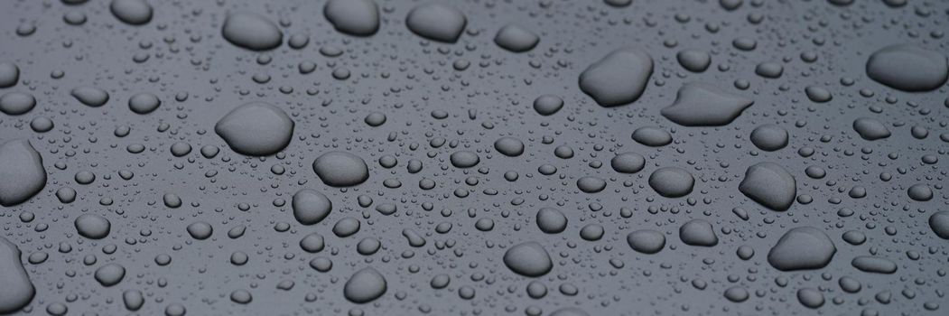 Closeup of raindrops on dark glass background. Oleophobic surface concept