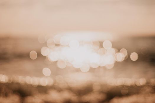 Abstract nature summer or spring ocean sea background. Small waves on water surface in motion blur with bokeh lights from sunrise.