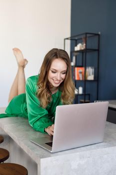 young smiling woman in dress working at home with laptop and champagne. High quality photo