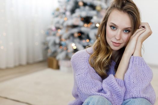 Portrait of a young woman at home near christmas tree. High quality photo