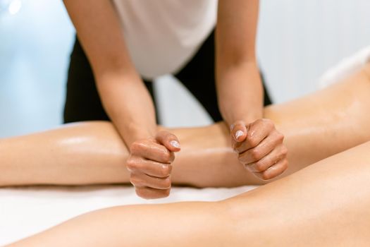 Woman receiving a leg massage with massage candle oil. Body care treatment in a beauty centre.