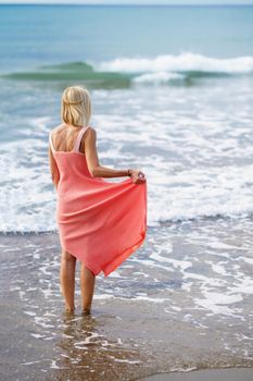 Older woman enjoying her free time looking at the sea from the shore of the beach.. Elderly female enjoying her retirement at a seaside retreat.