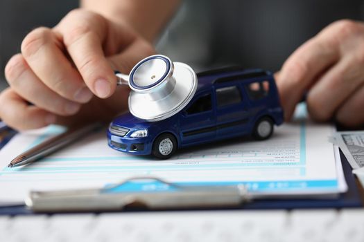 Close-up of man use car with stethoscope tool, symbol of car insurance or maintenance service. Protect automobile with insurance. Checkup, repair concept