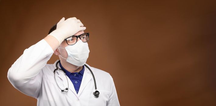 panoramic Young caucasian doctor in a medical uniform makes a facepalm gesture. Medical errors and stupidity.