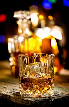 Glass of whiskey and decanter on wooden table