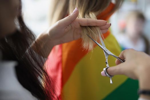 Close-up of woman holding lock of hair and cutting with scissors equipment. Female help with hairstyle her girlfriend at home. Lgbt, beauty, image concept