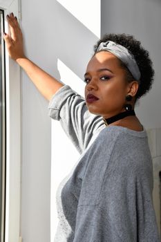 A pretty young African American confident woman in the stairwell of an old apartment building.